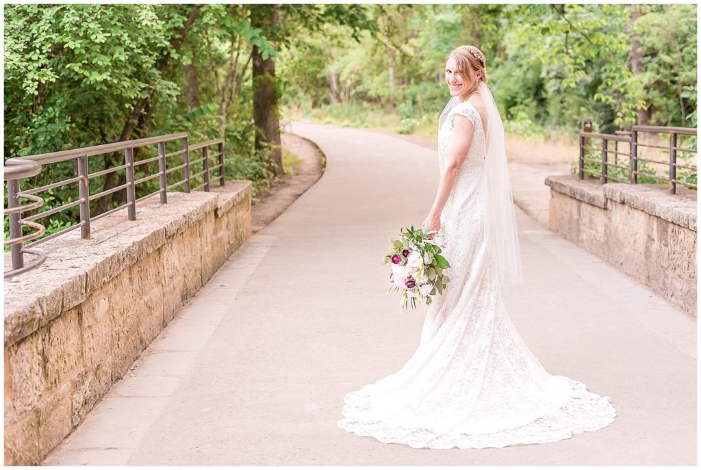 bride on path through the woods in lace davids bridal gown