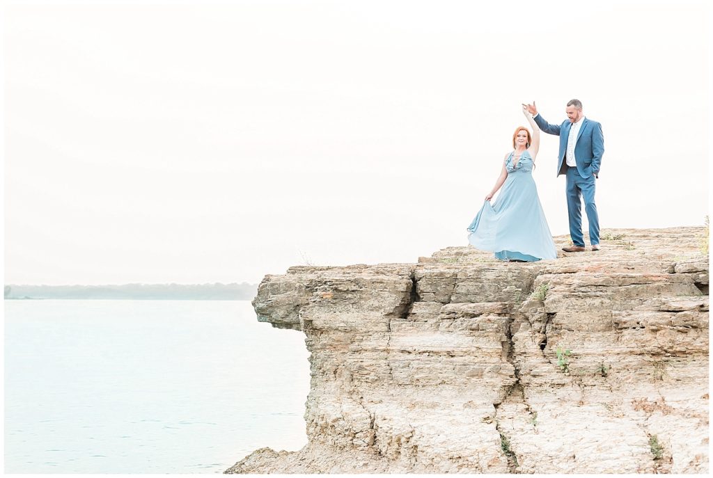 engaged couple twirling dancing on cliff at rockledge park in grapevine texas blue dress