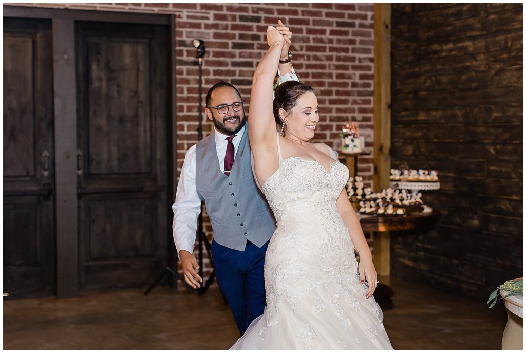 bride and groom dancing in brick and dark wood shiplap venue first dance