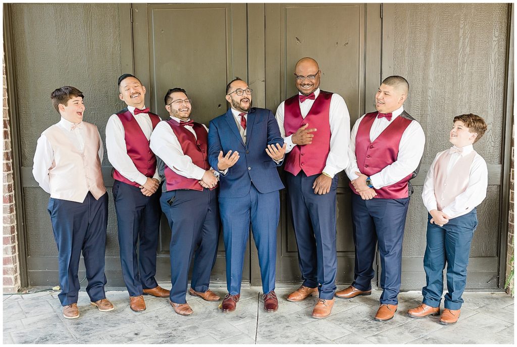 groom and groomsmen burgundy vests burgundy ties navy suits