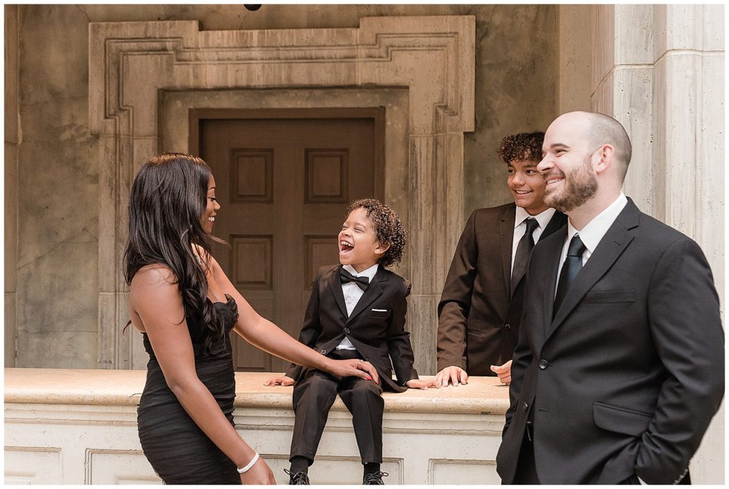 family in black dress and tuxedos laughing