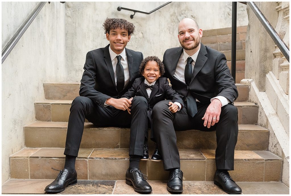 father and sons in tuxedos on stairs