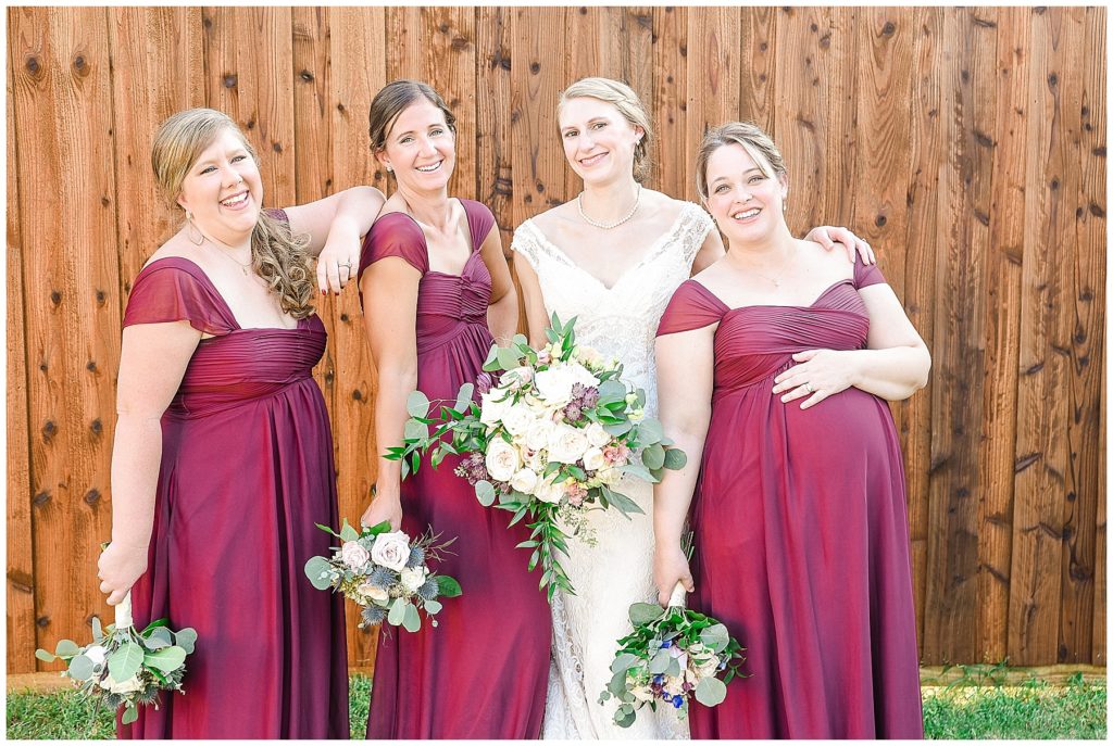 bride in lace with bridesmaids in burgundy dresses with white rose bouquets
