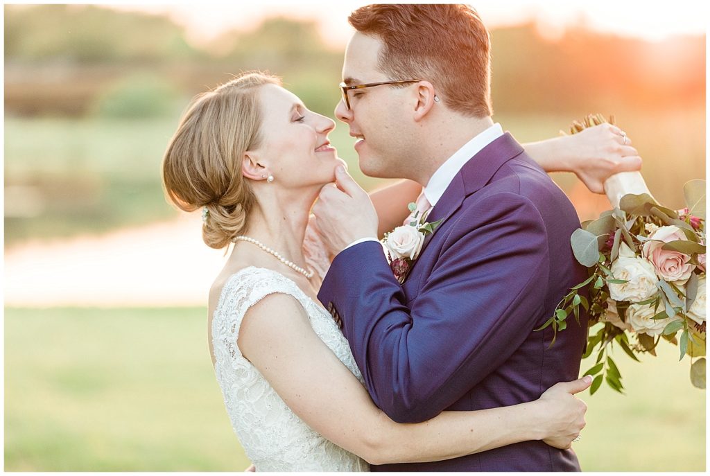 bride and groom in navy suit kissing at sunset golden hour glow