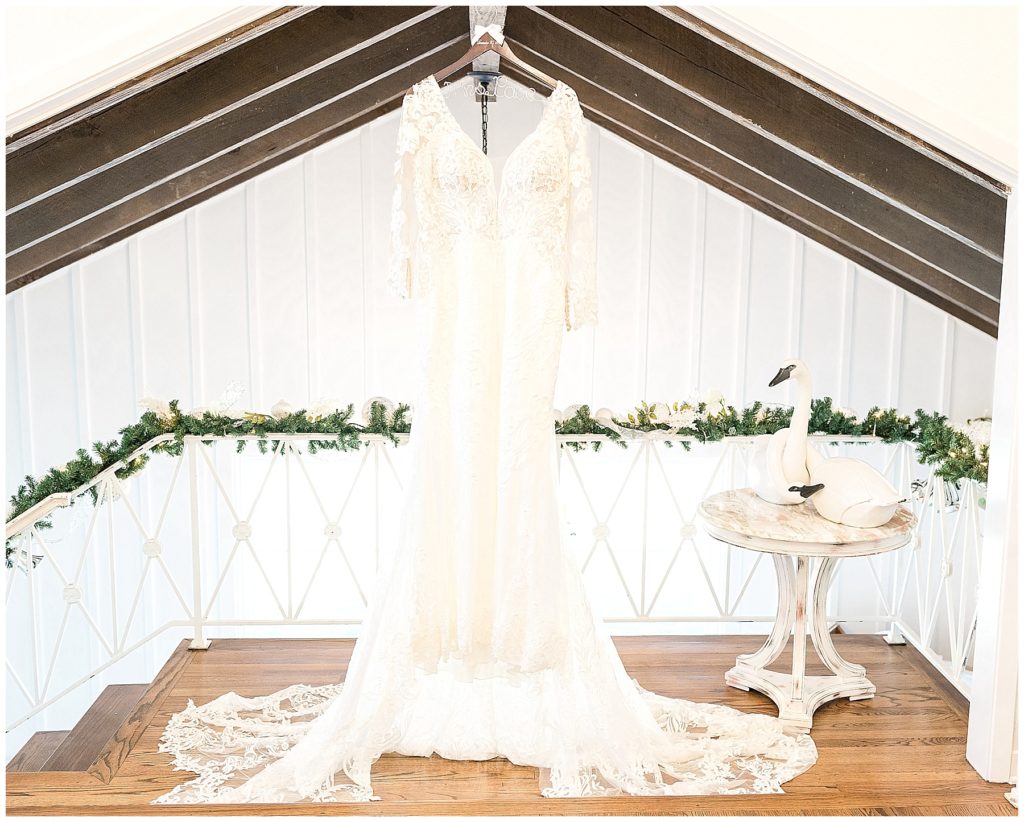 white lace wedding gown hanging from exposed beams