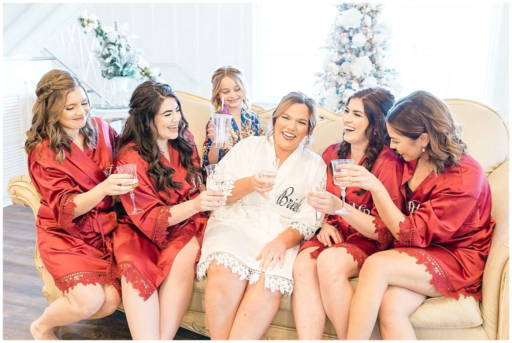 bride and bridesmaids in matching robes laughing and champagne toast