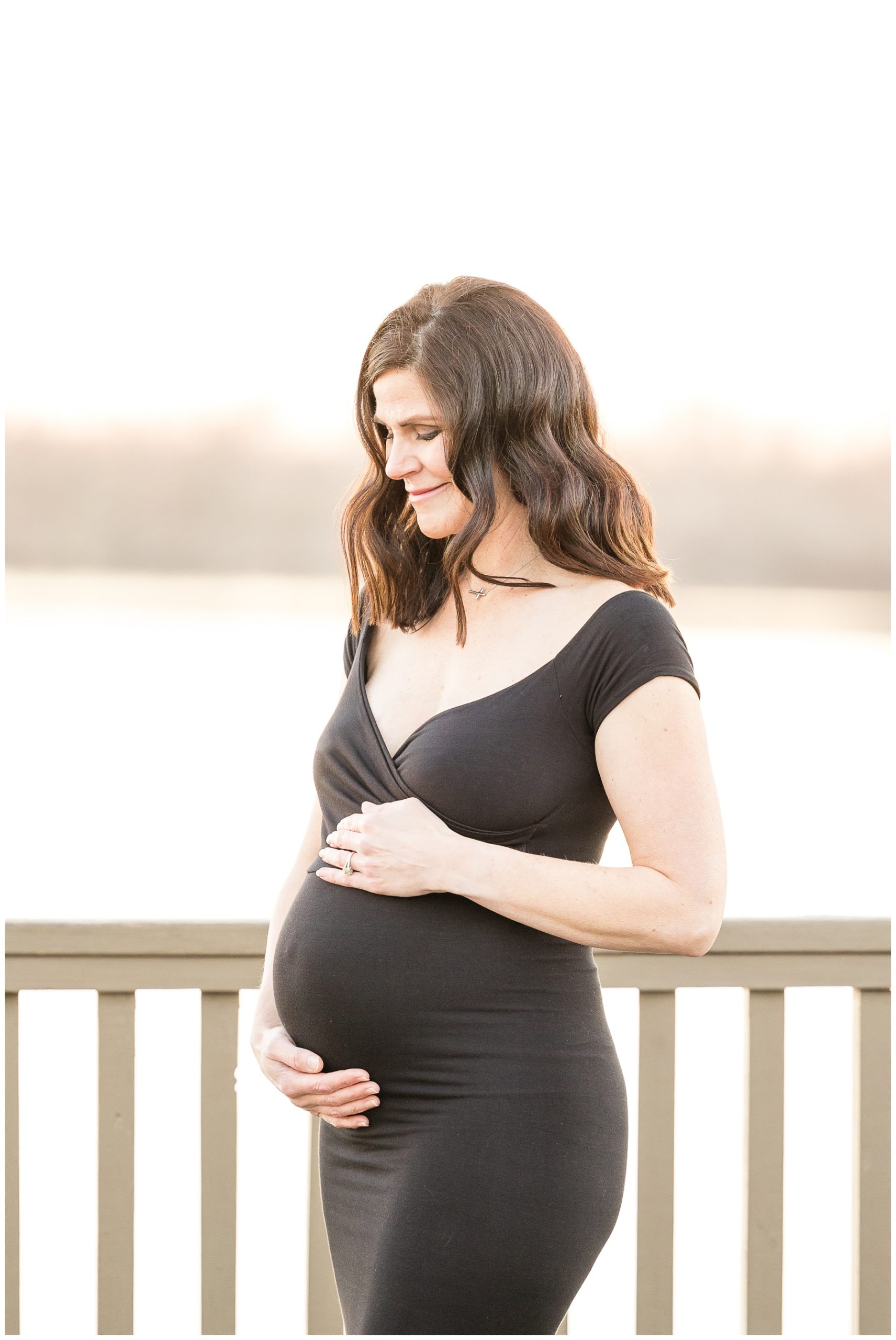 expectant mother poses by Red River in black gown