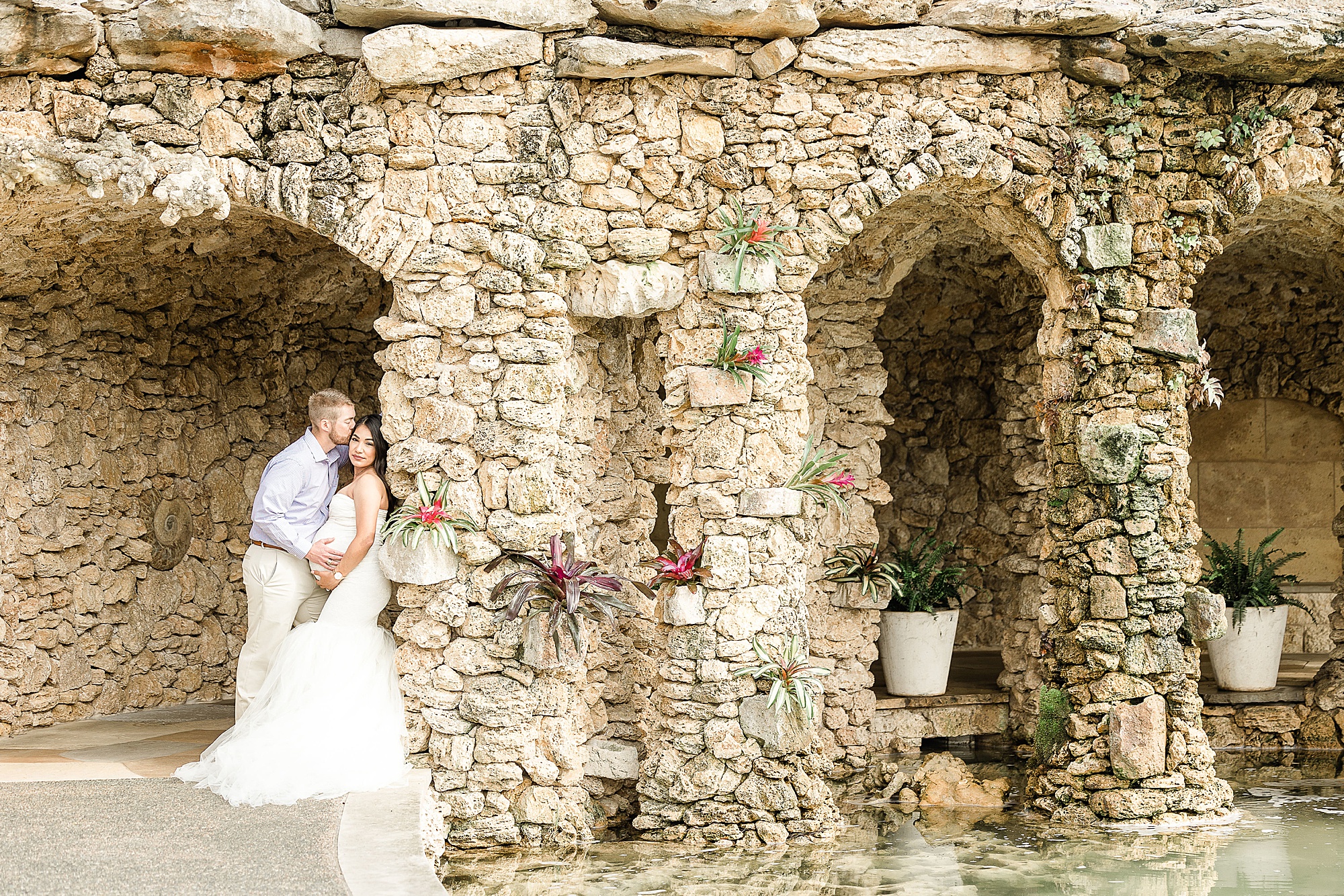 couple poses in grotto of Dallas Arboretum during maternity photos
