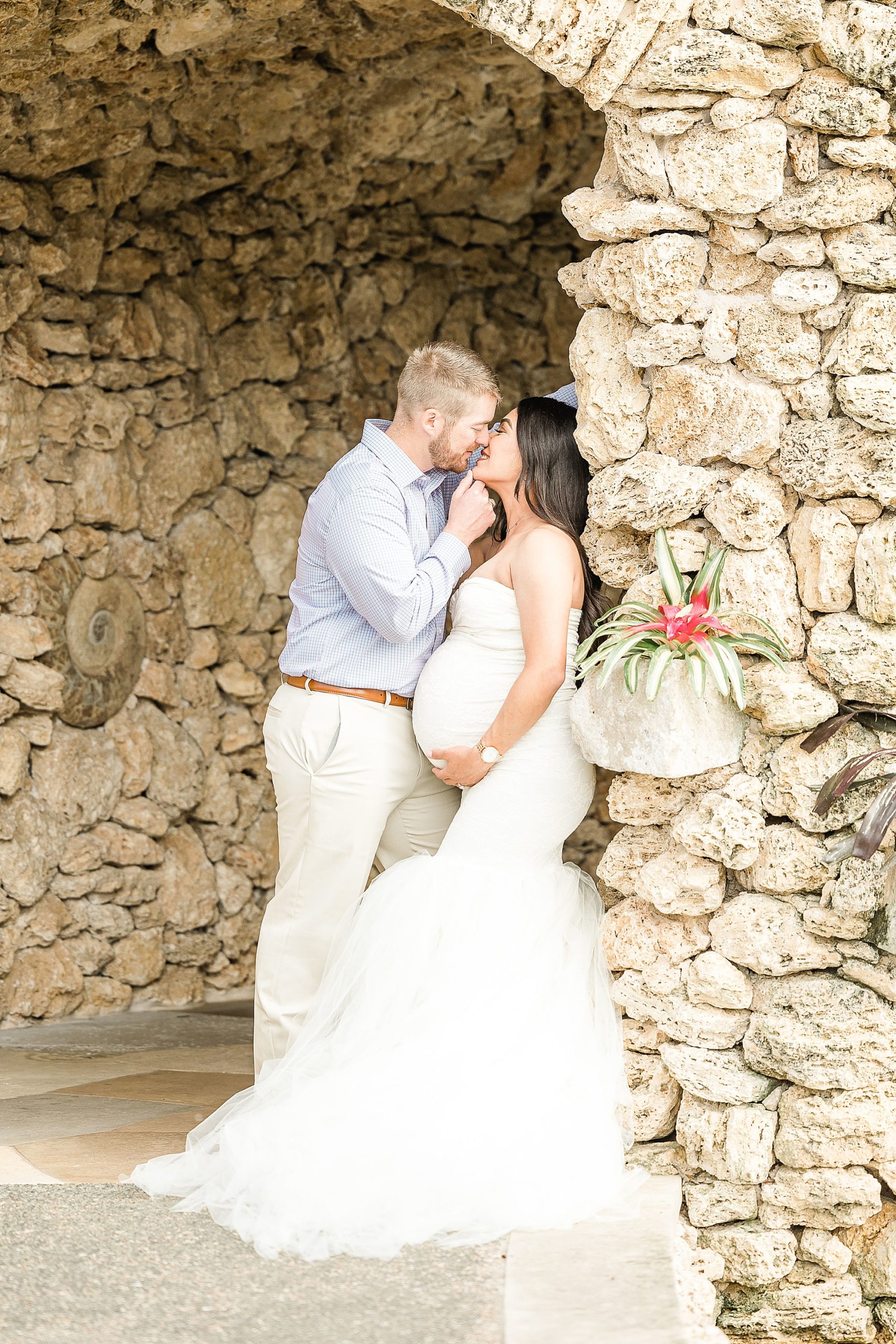 husband and wife kiss against stone wall at Dallas Arboretum
