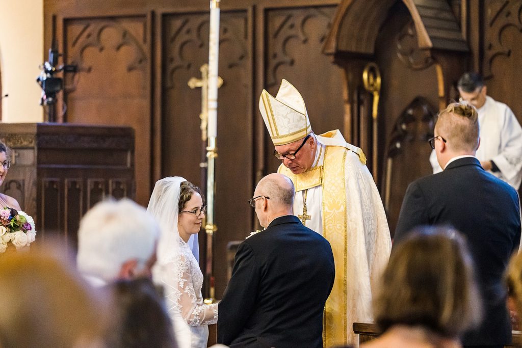 couple exchanges vows during traditional church wedding at the Church of Holy Communion