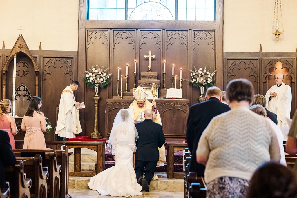 couple kneels during traditional church wedding at the Church of Holy Communion