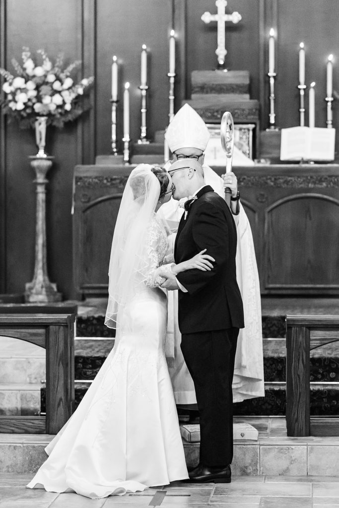 bride and groom kiss after traditional church wedding at the Church of Holy Communion