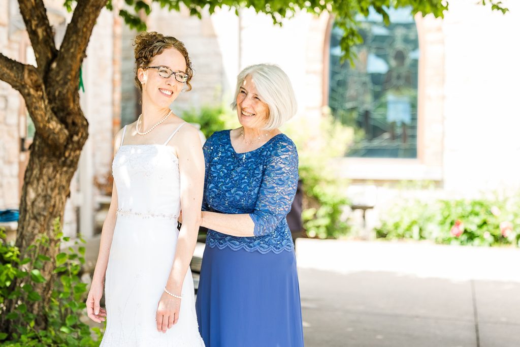 mom helps bride with wedding dress