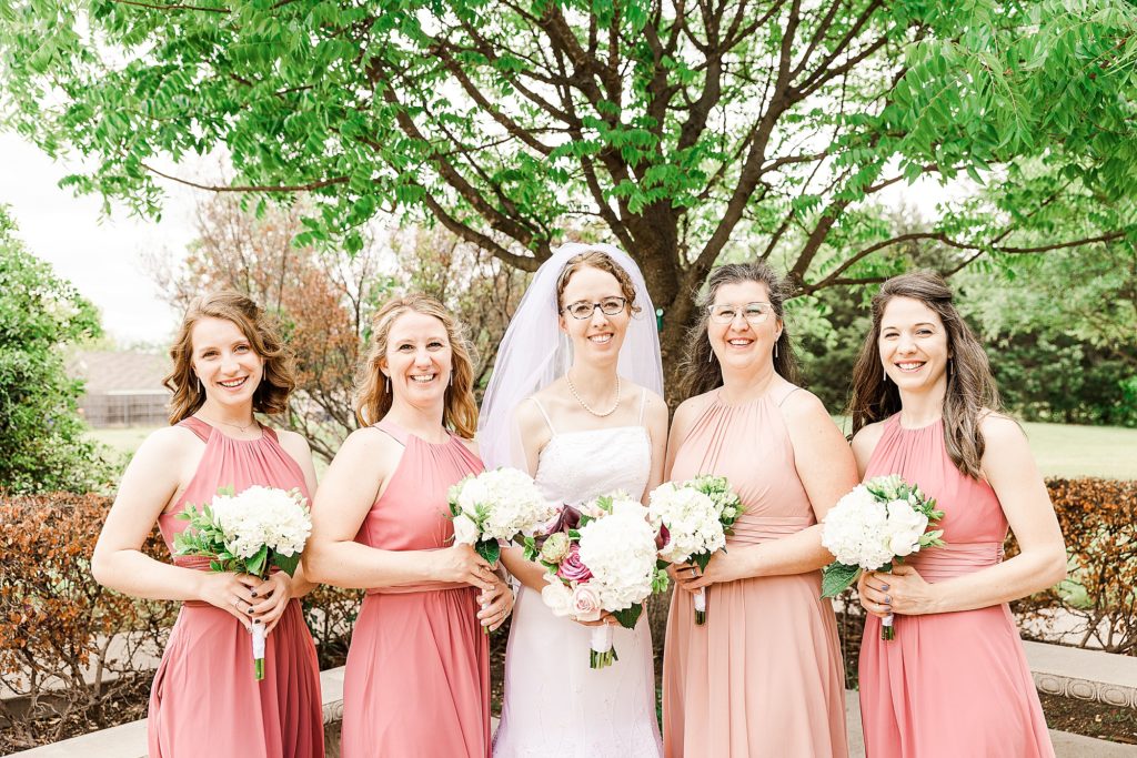 bride poses with bridesmaids in peach dresses 