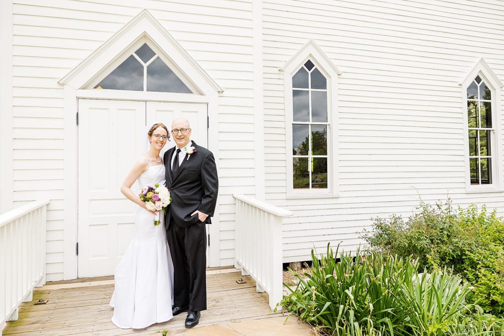 bride and groom hug outside white chapel