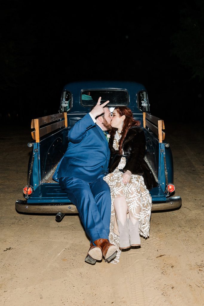 bride and groom kiss on back of vintage blue truck