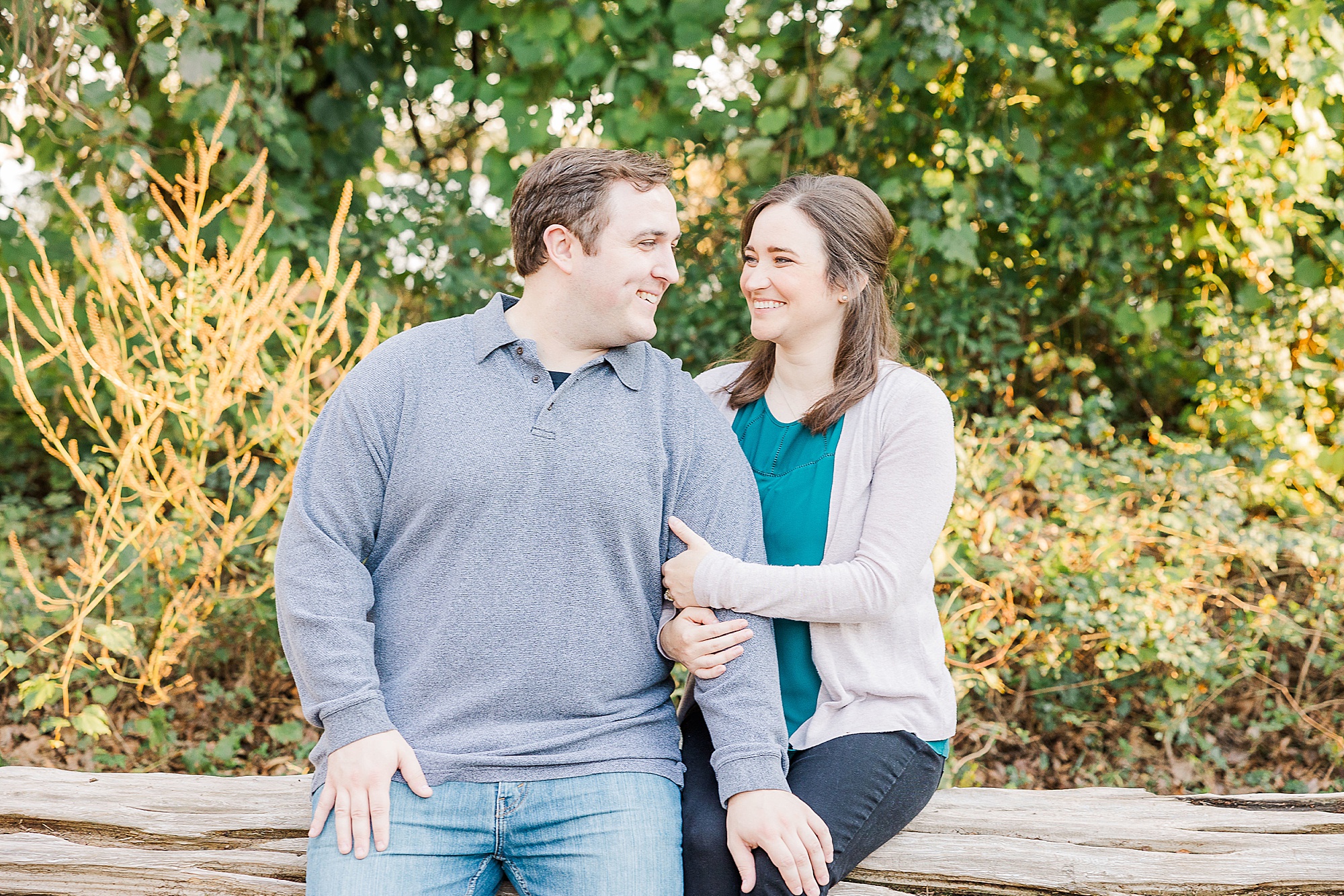 engaged couple sits on log during engagement session in Louisiana