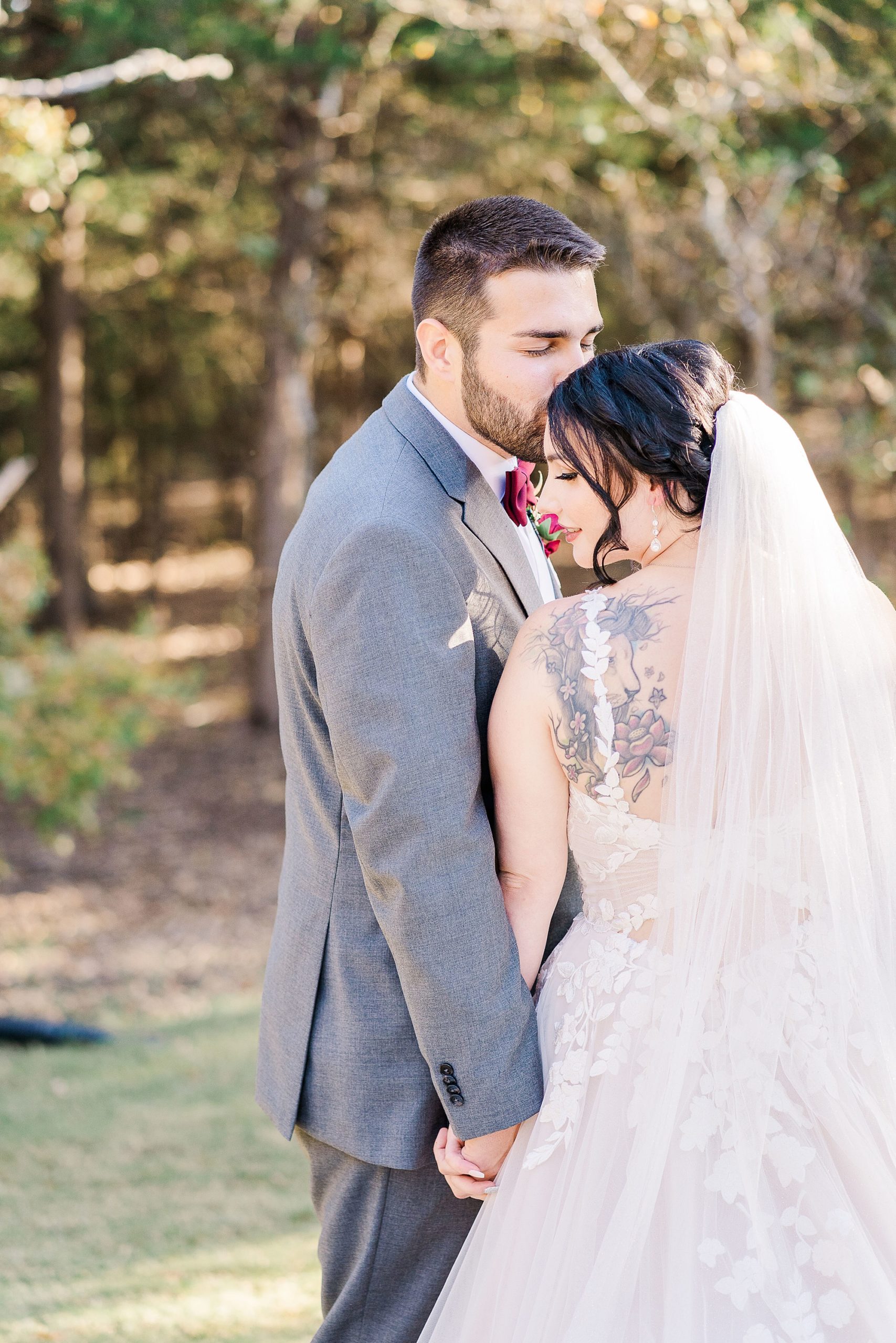 bride leans on groom's shoulder while he kisses her forehead