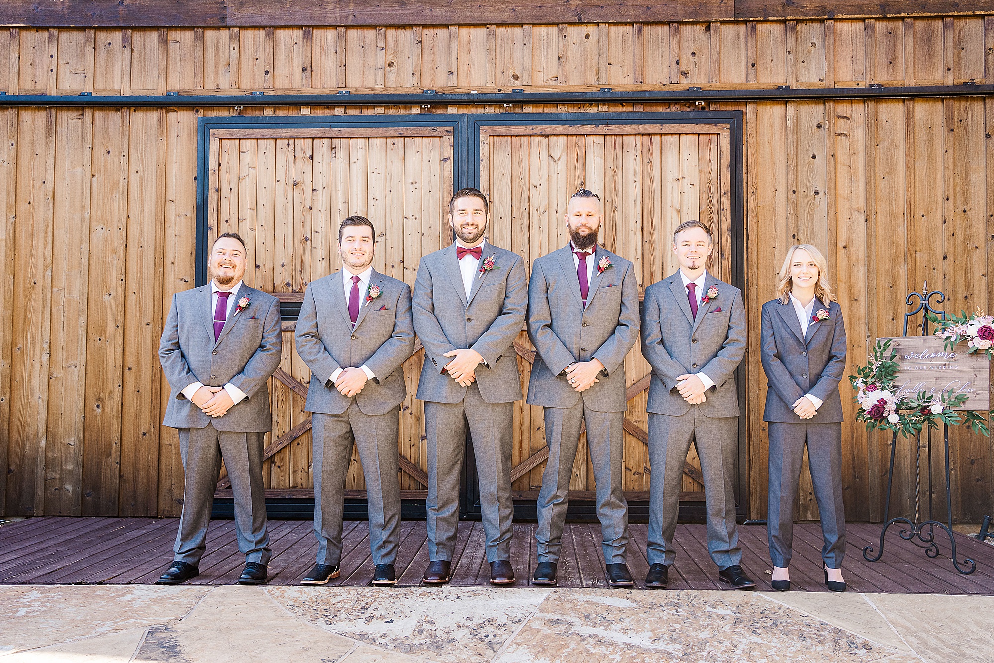 groom poses with groomsmen beside barn door