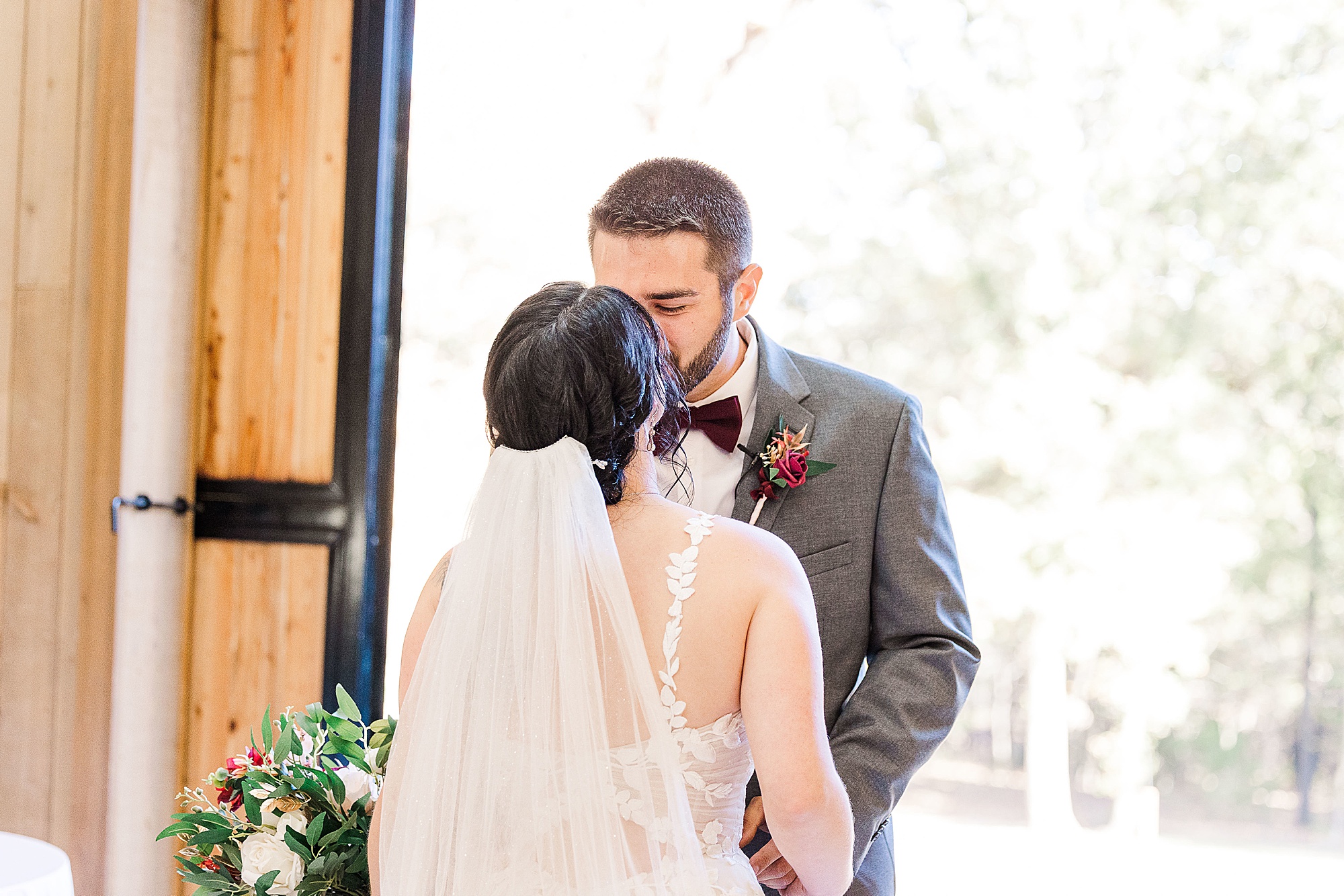 bride and groom kiss during first look at Whispering Oaks