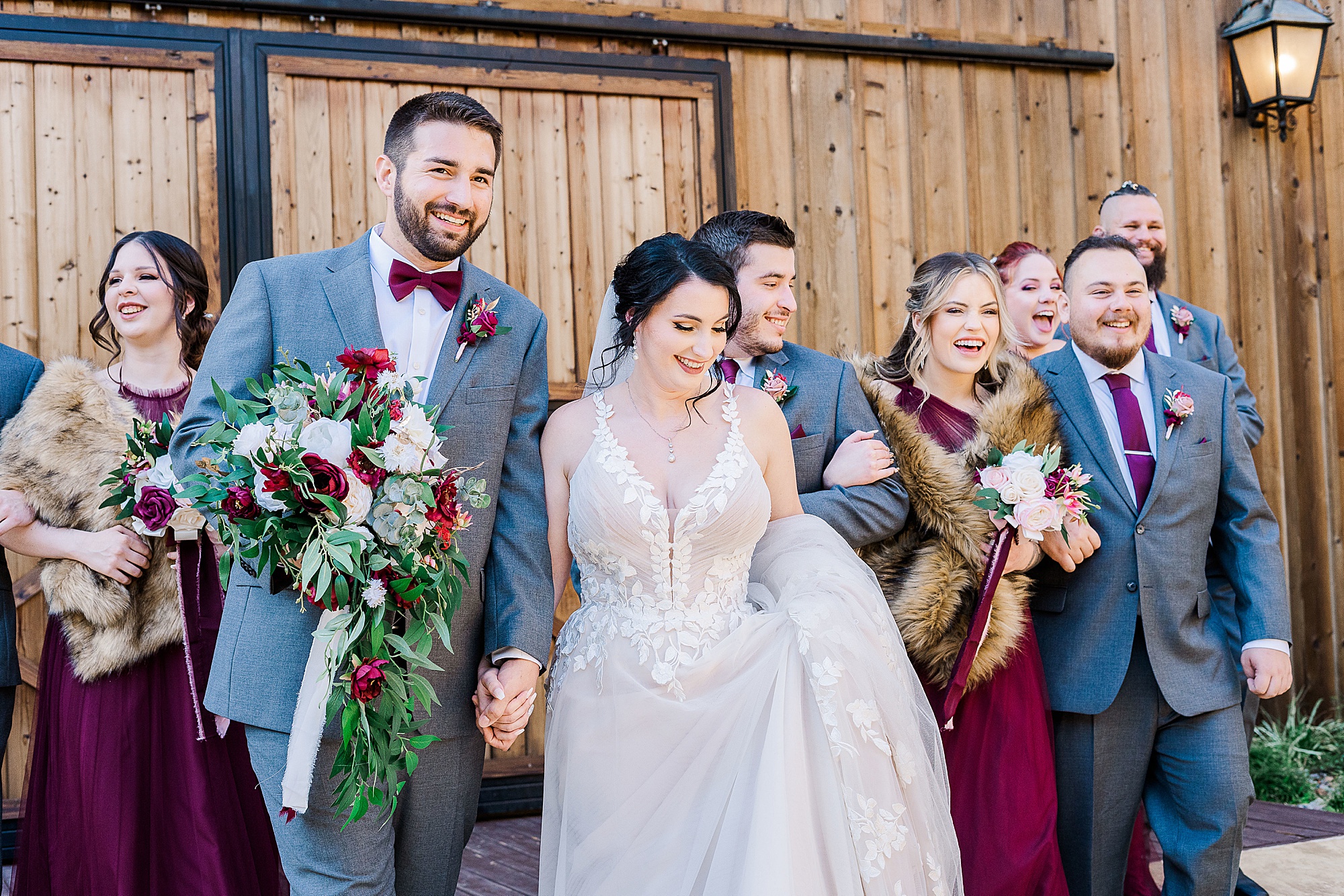groom holds bride's bouquet during portraits with their wedding party