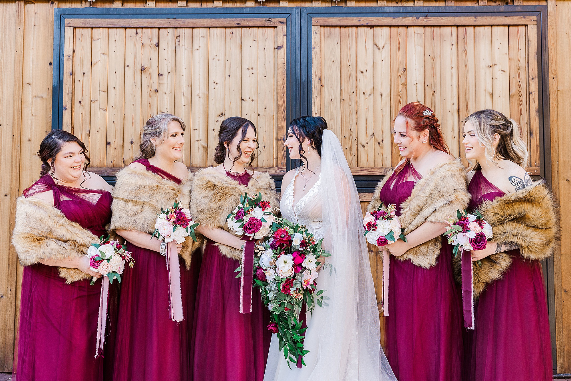 bride laughs with bridesmaids in burgundy gowns