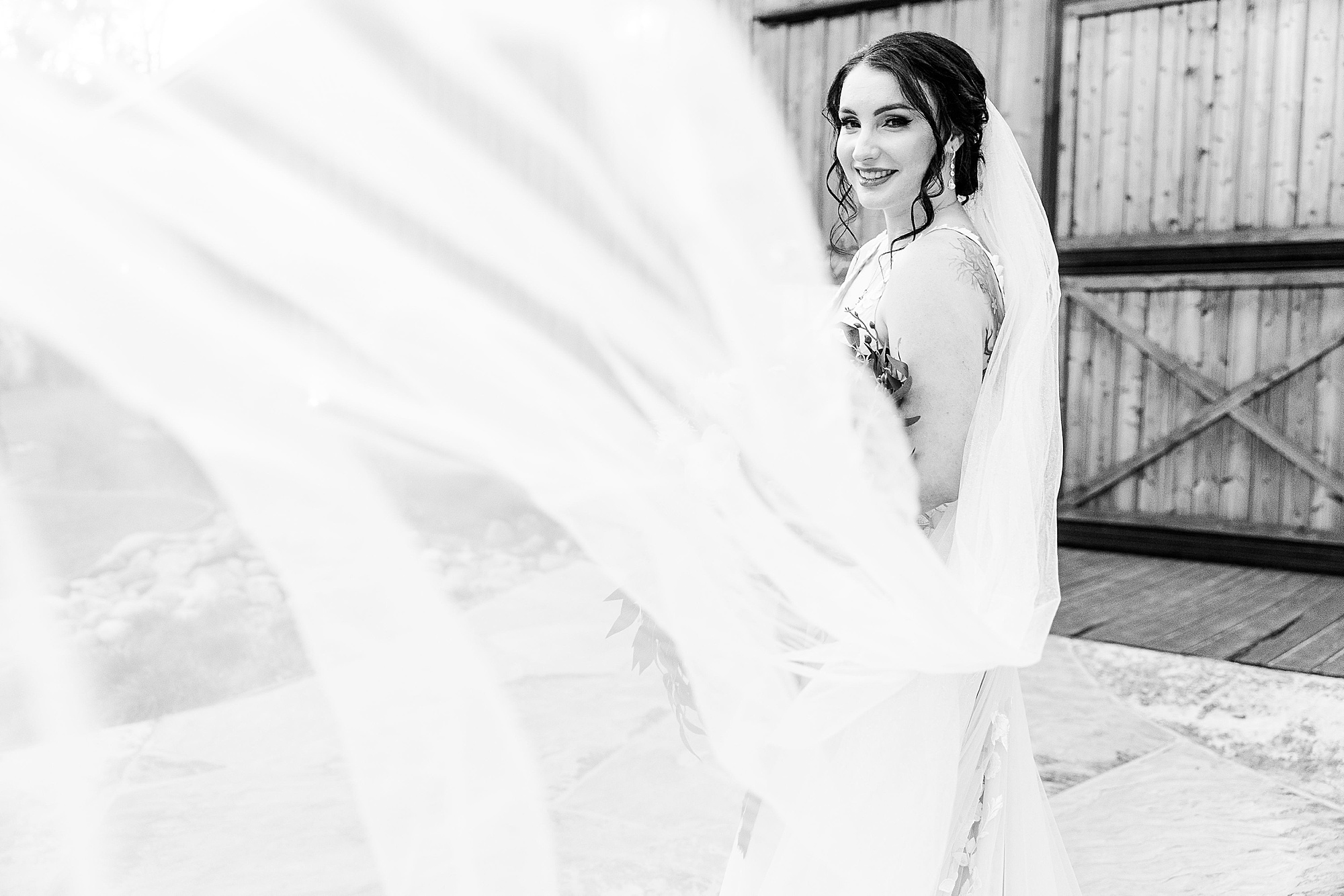 bride tosses wedding veil during portraits outside Whispering Oaks