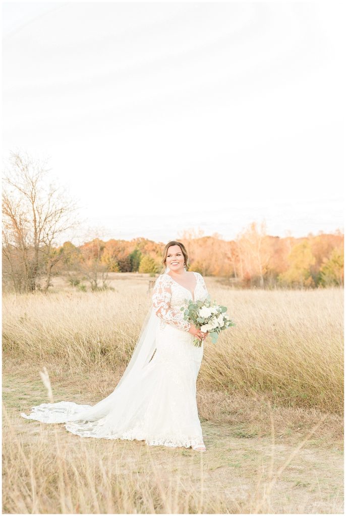 bride in lace dress and cathedral length veil in field in dallas texas