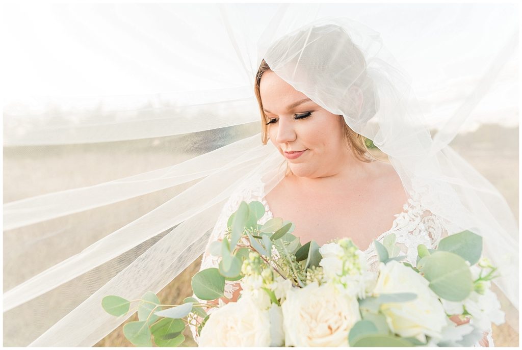 bride under cathedral veil with white rose bouquet