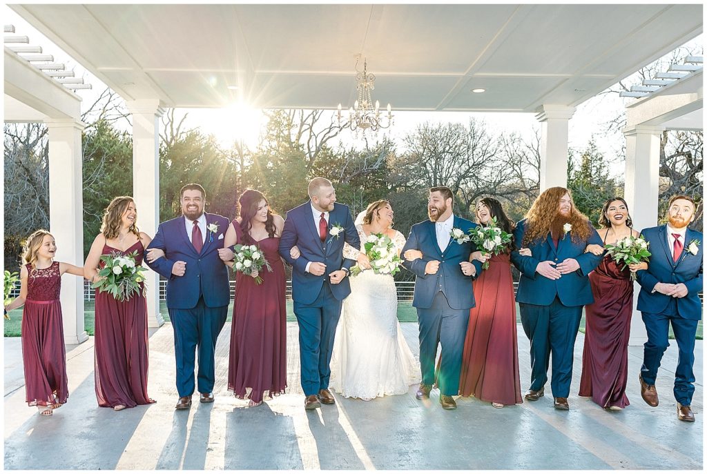 laughing wedding party in burgundy dresses and navy suits