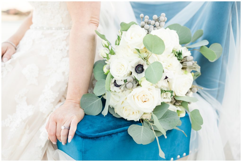 bridal bouquet with white roses and white anemones on blue velvet chair