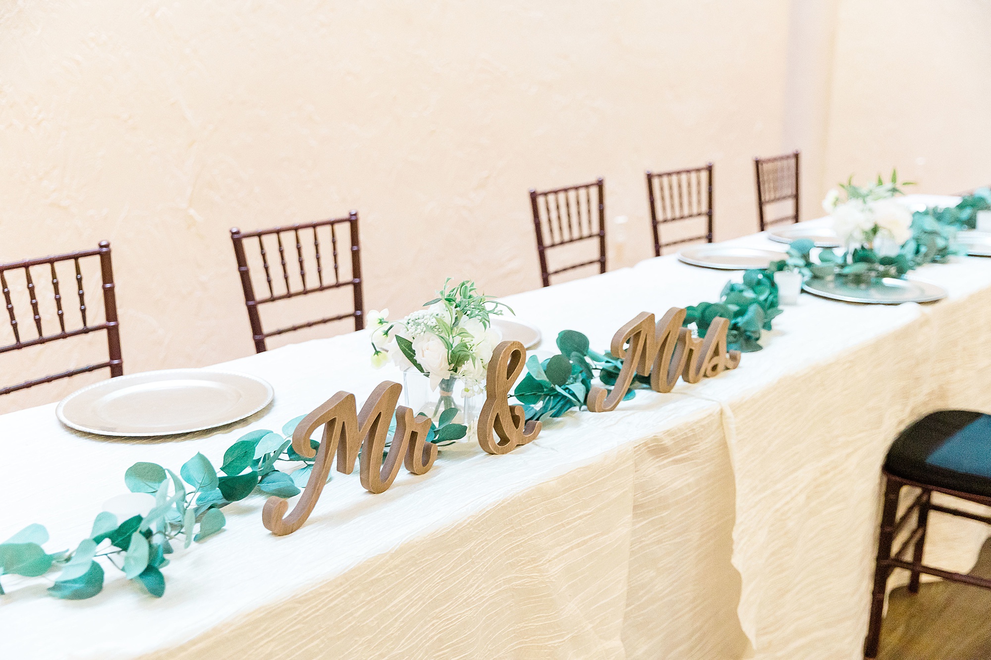 head table with MR and Mrs gold signs with greenery