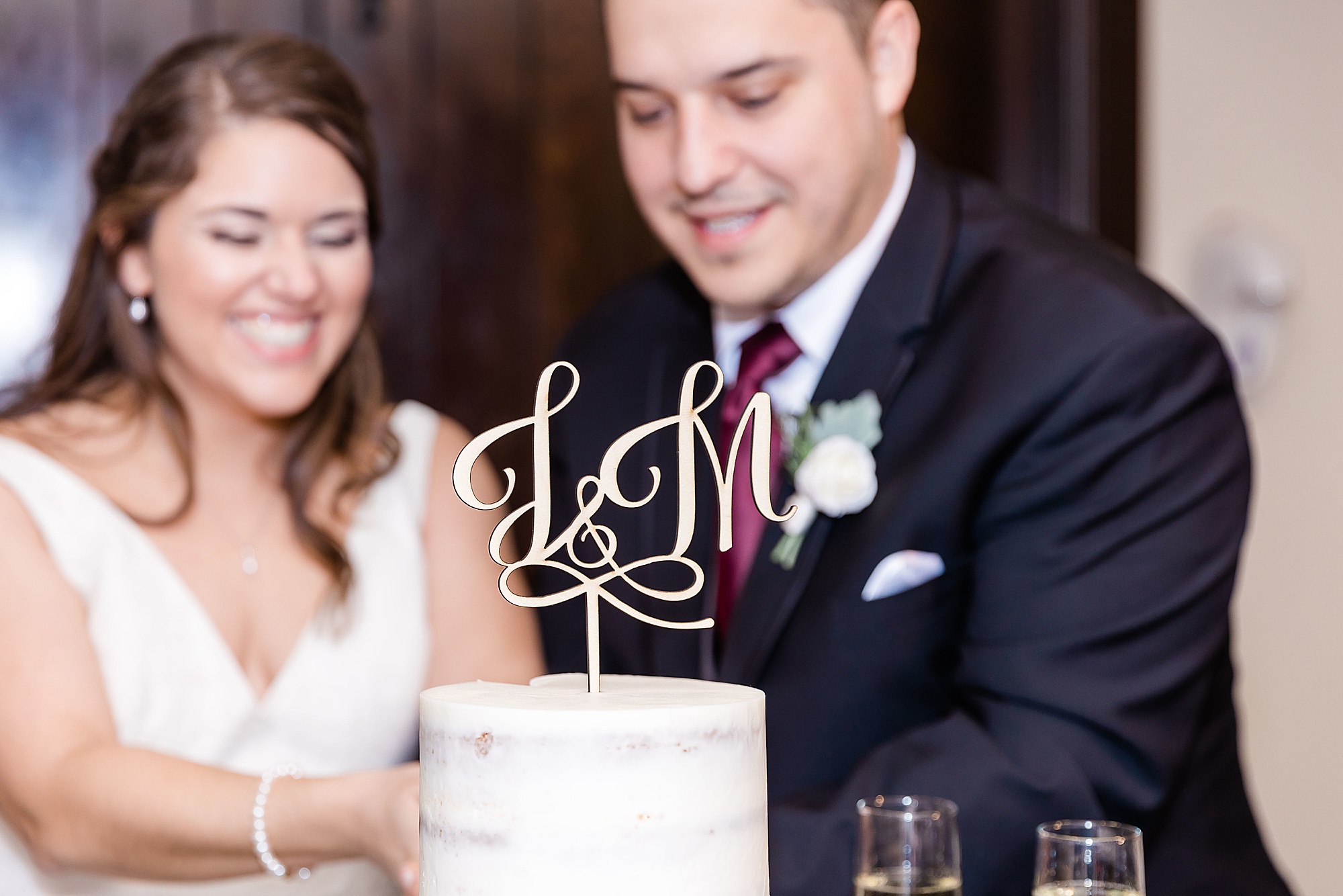 newlyweds cut wedding cake with gold topper 
