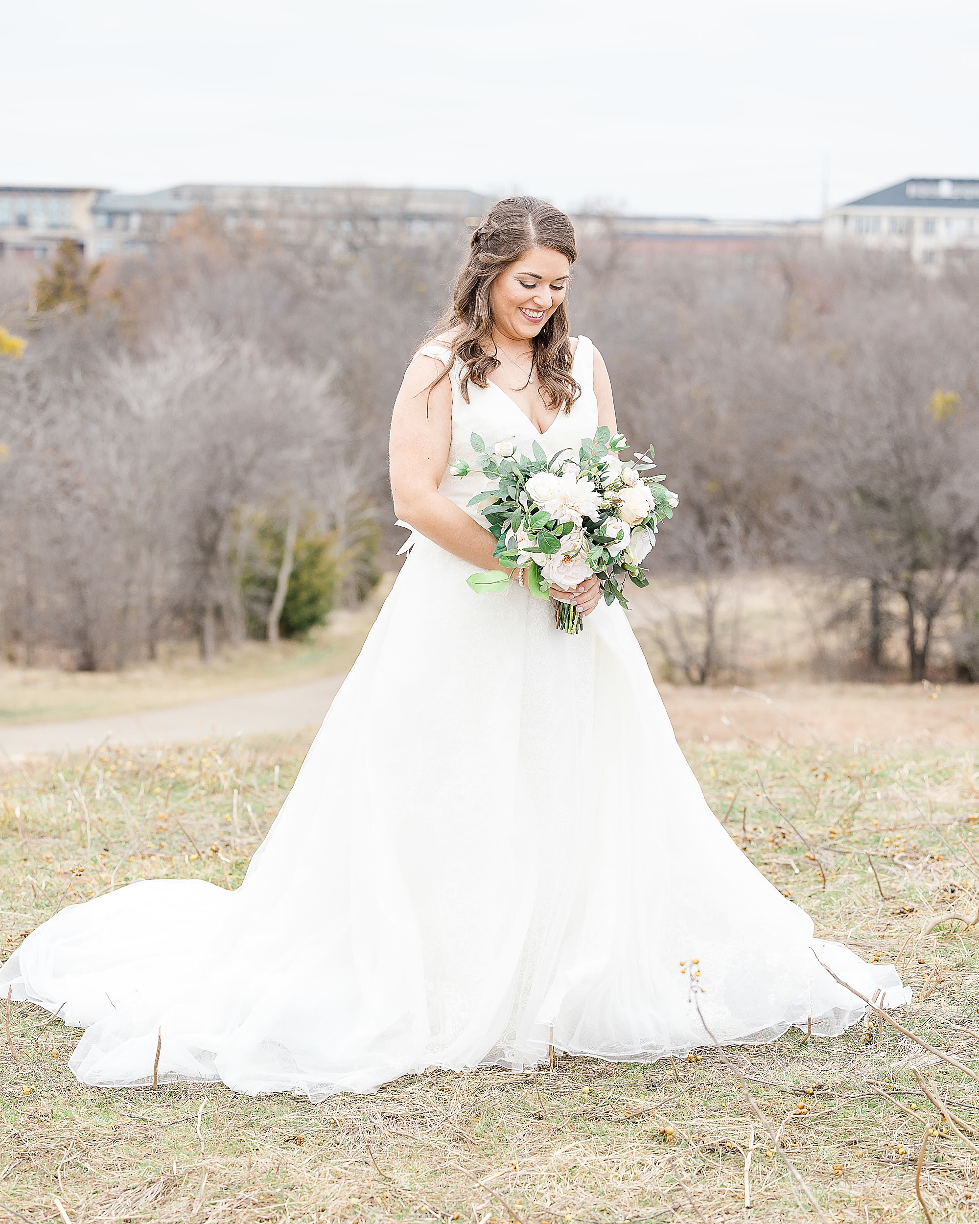 bride looks down at bouquet of white flowers at Arbor Hills Nature Preserve