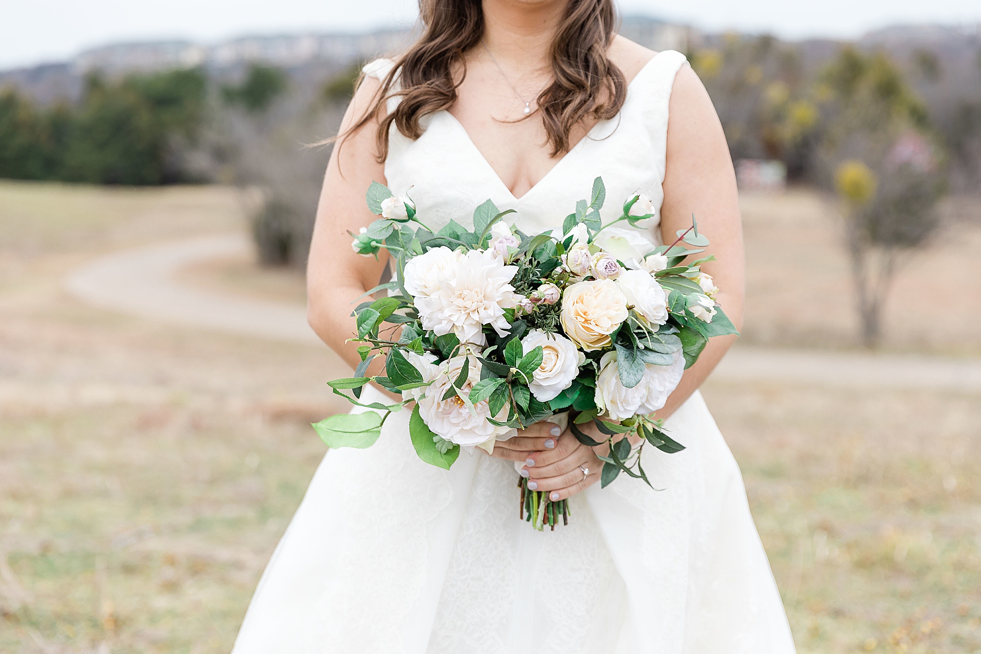bride holds bouquet of light and white flowers for winter wedding