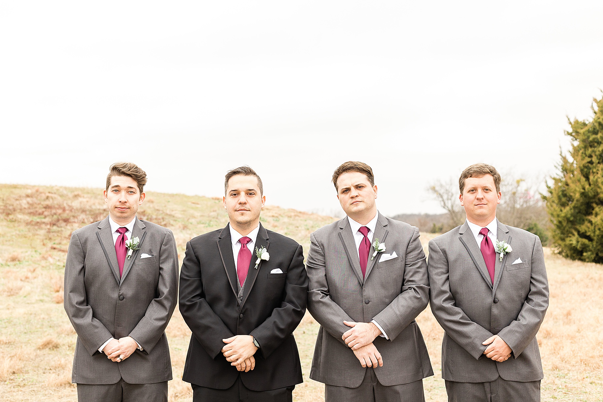 groom poses with three groomsman in grey suits