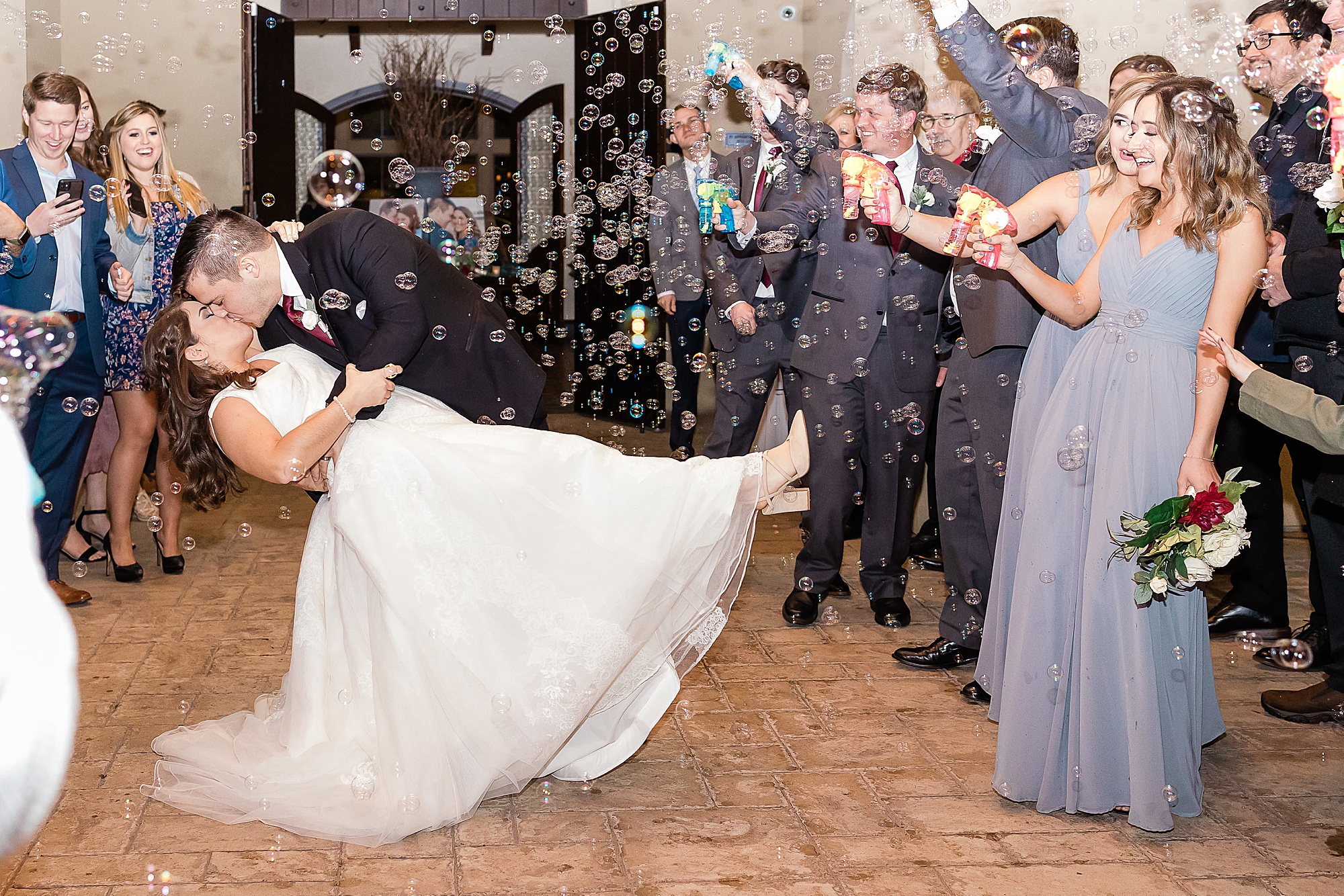 groom kisses bride dipping her during bubble exit 