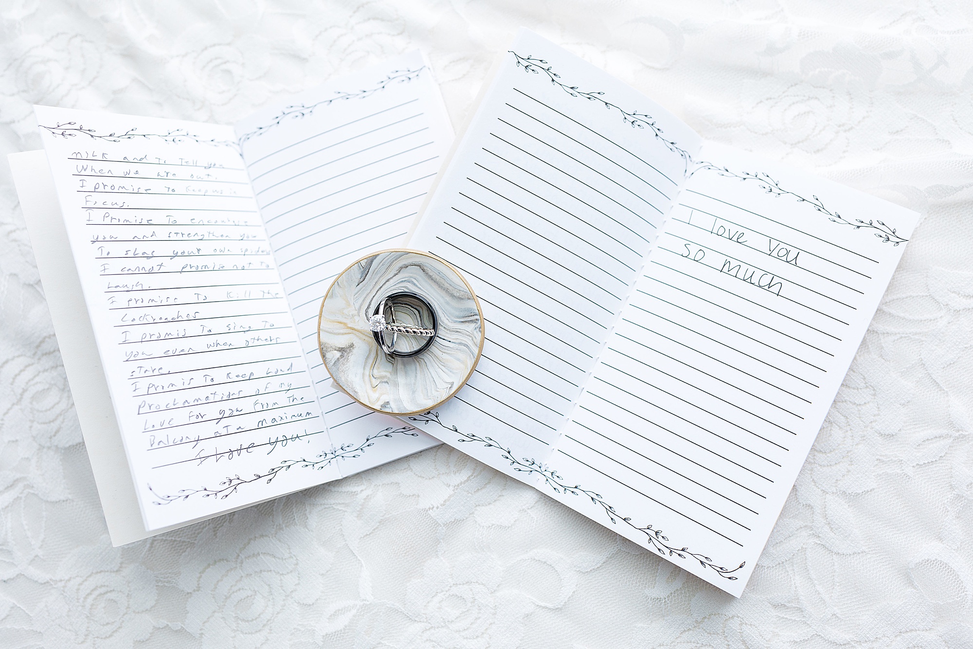 wedding rings sit on vow booklets 
