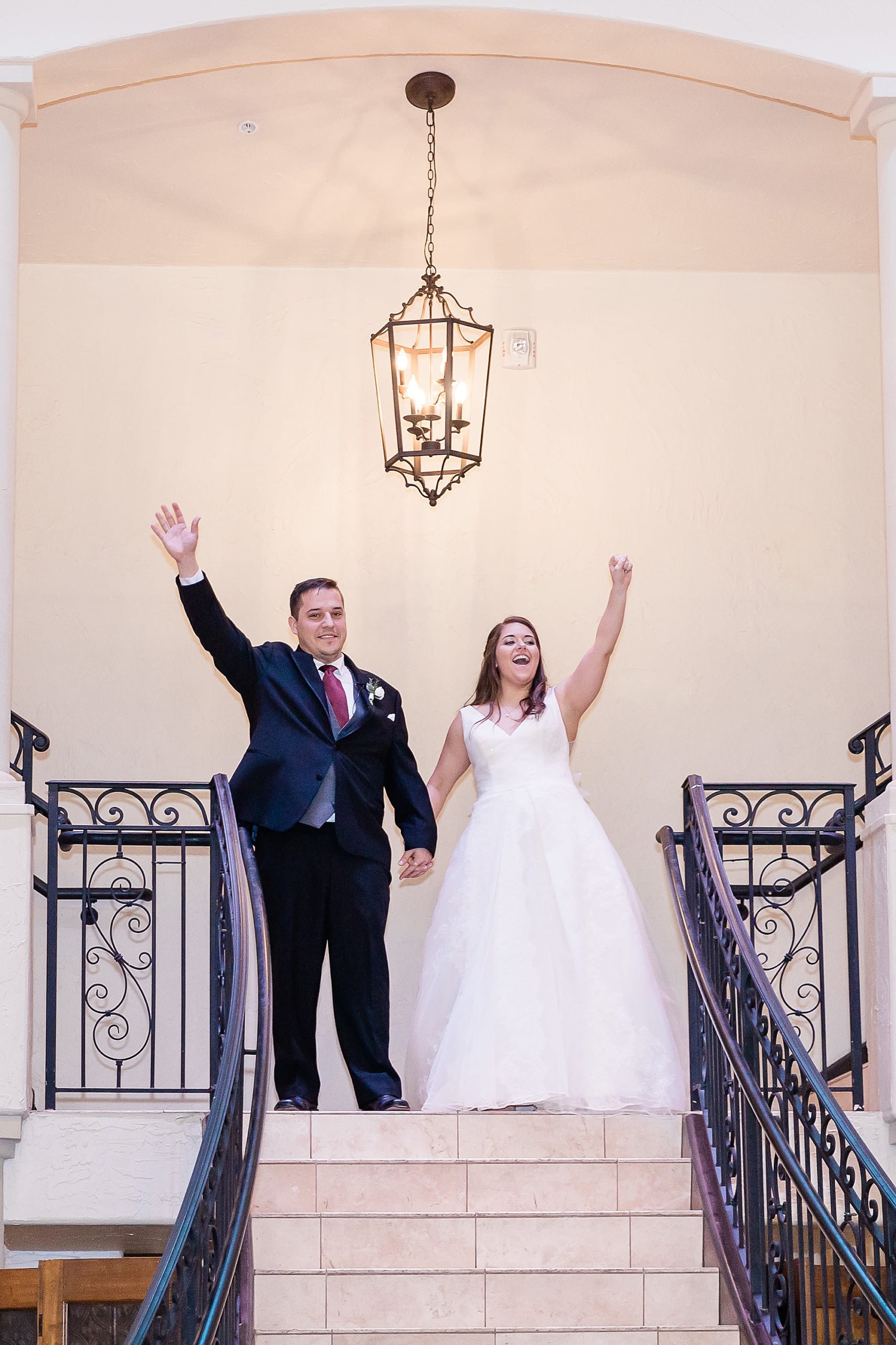newlyweds cheer on top of staircase at Texas wedding reception