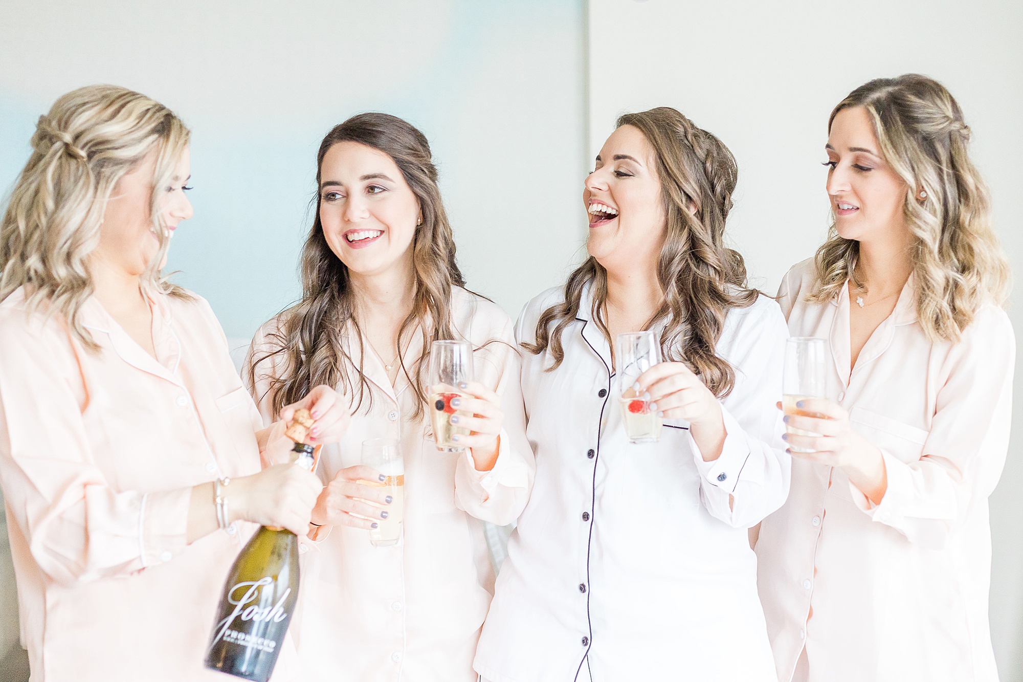 bride laughs with bridesmaids during champagne toast