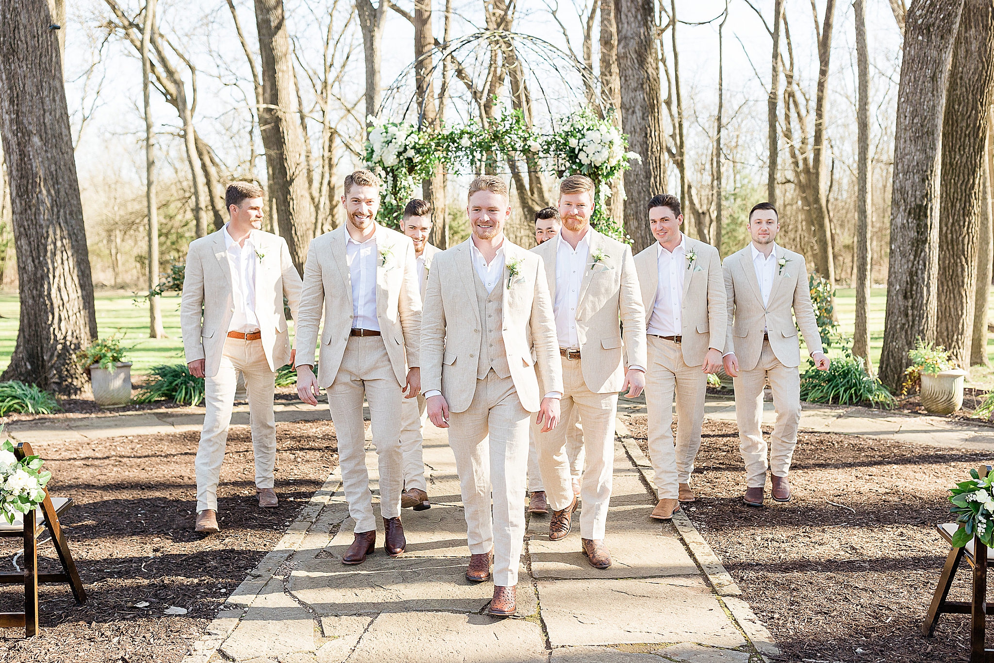 groom walks with groomsmen in tan suits