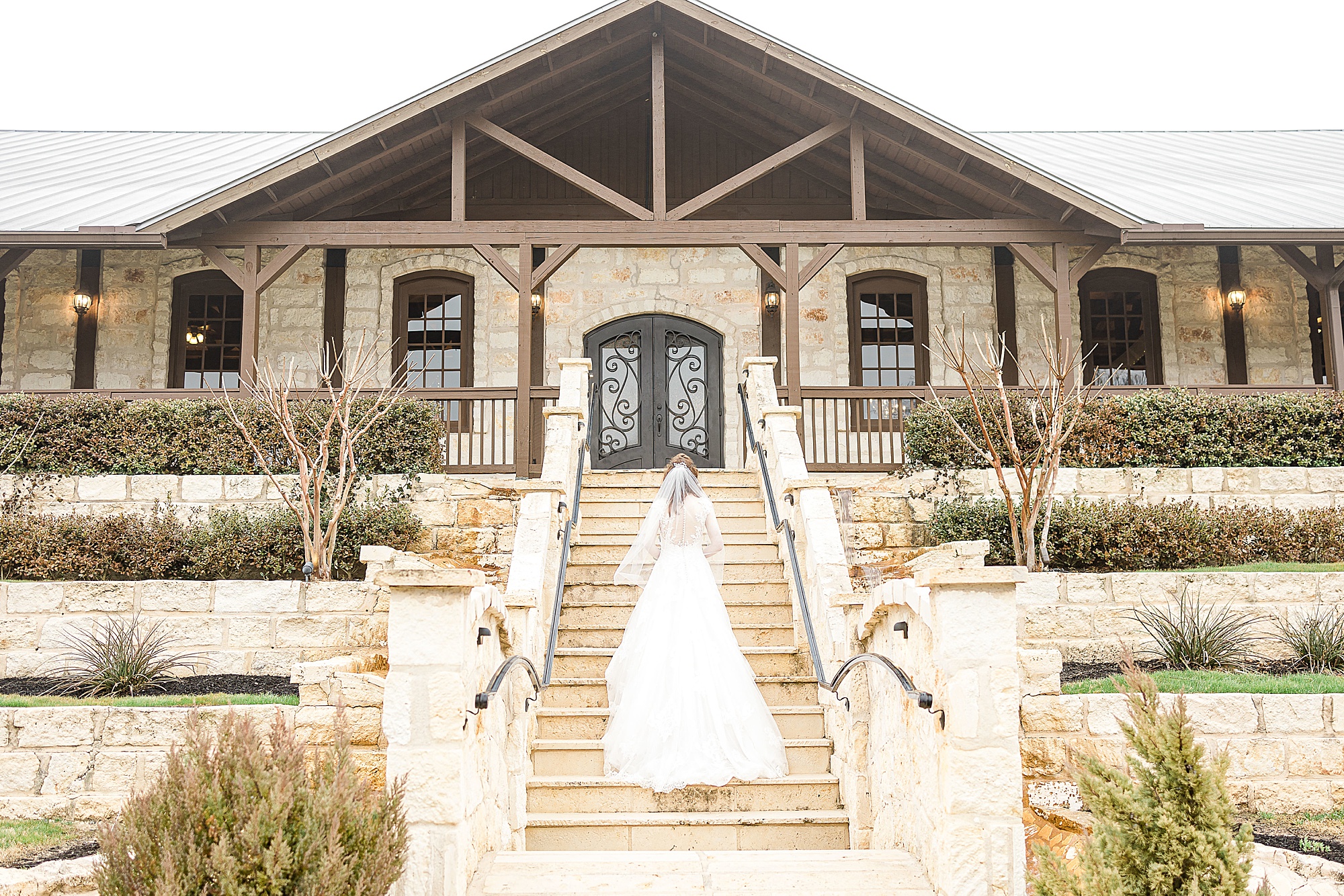 bride walks up steps outside Stone Hall at the Springs