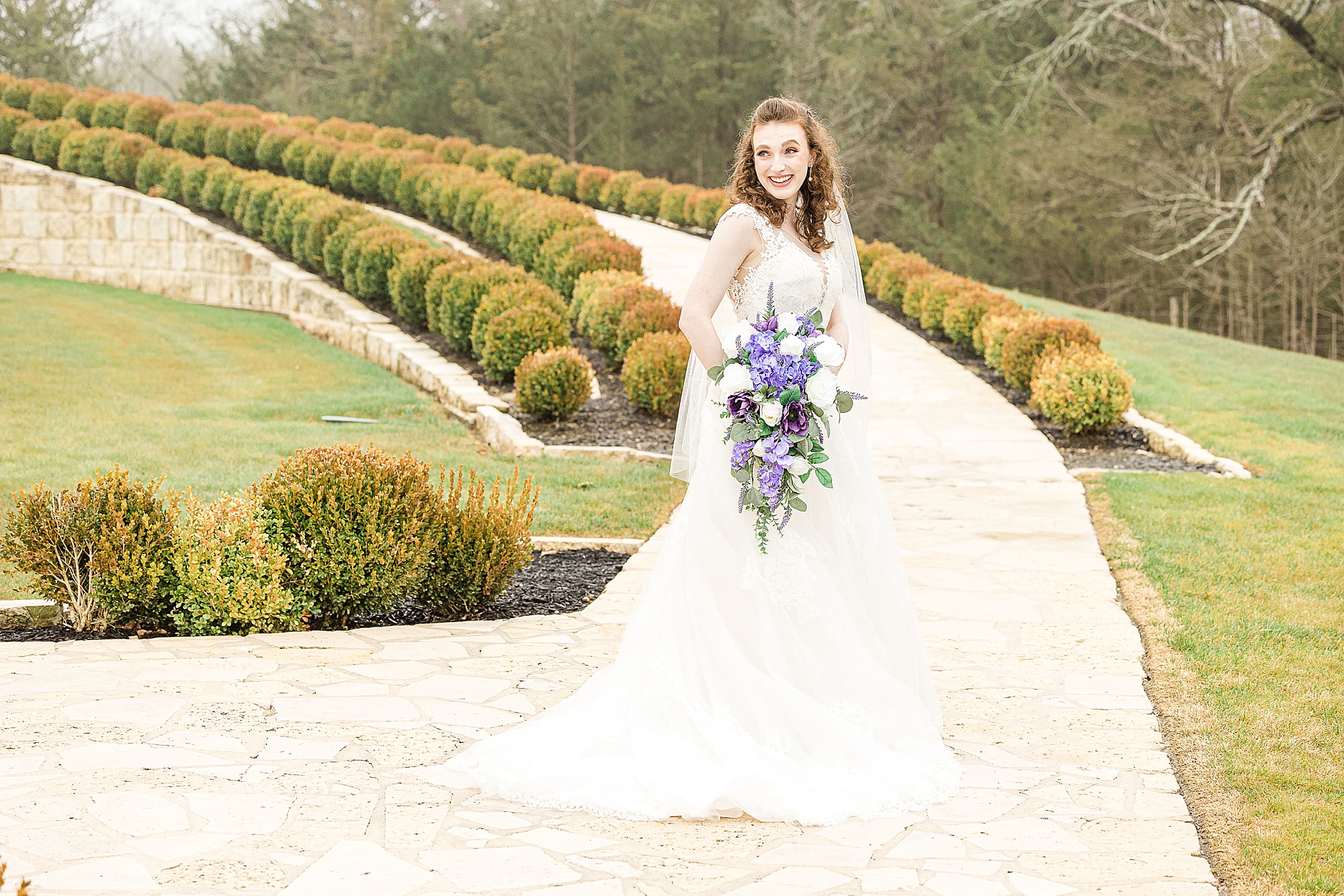 bride holds bouquet of purple flowers at Stone Hall at the Springs
