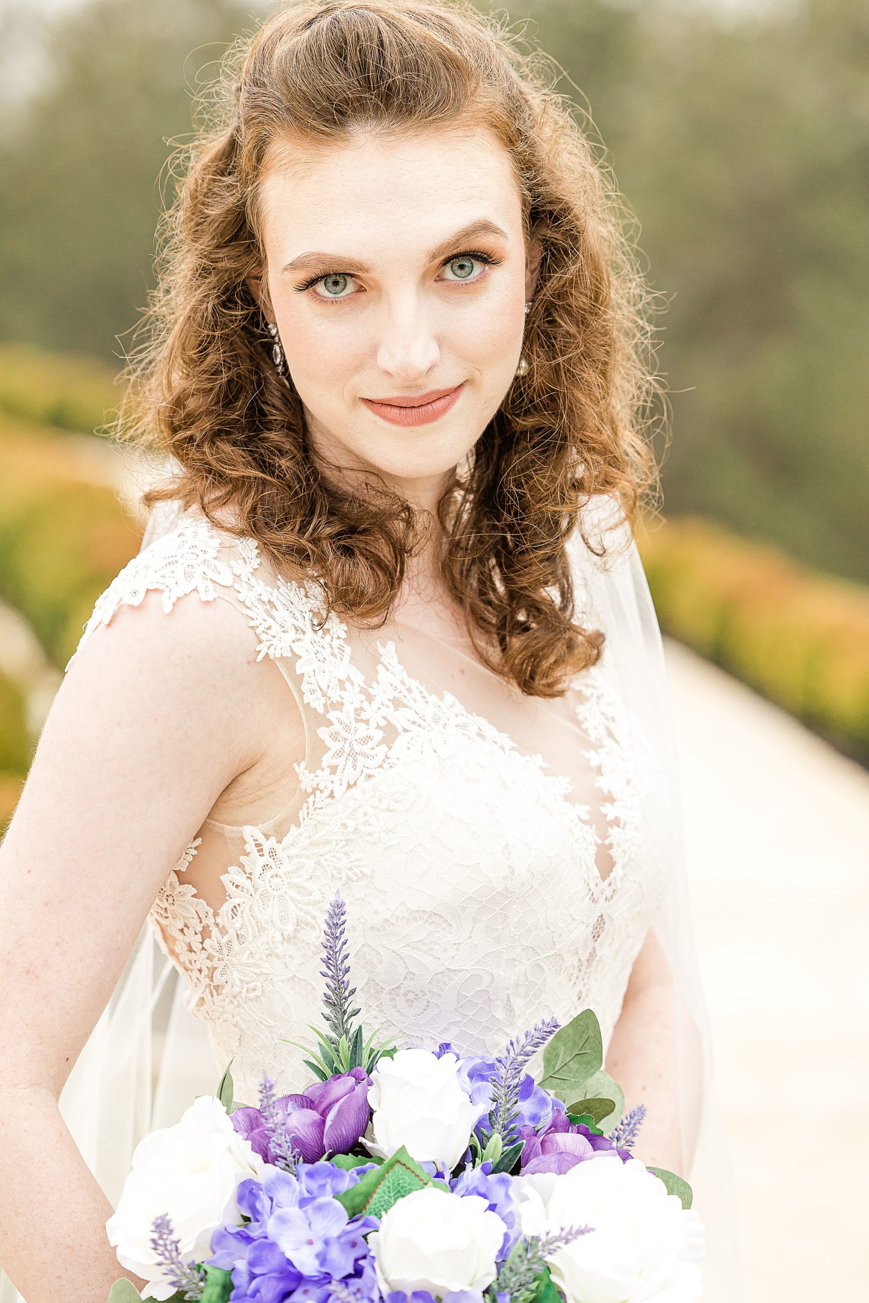 bride with bouquet of purple flowers smiles at camera