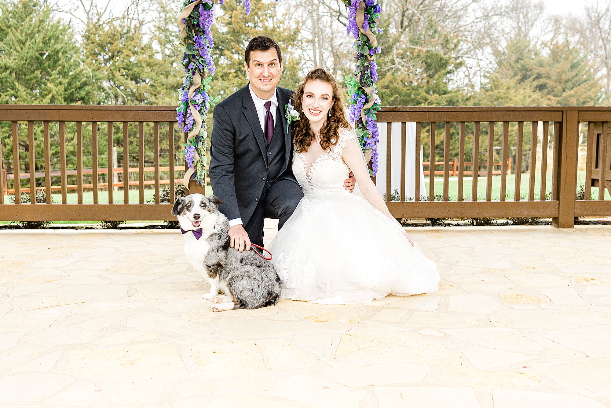 bride and groom sit with dog after wedding ceremony