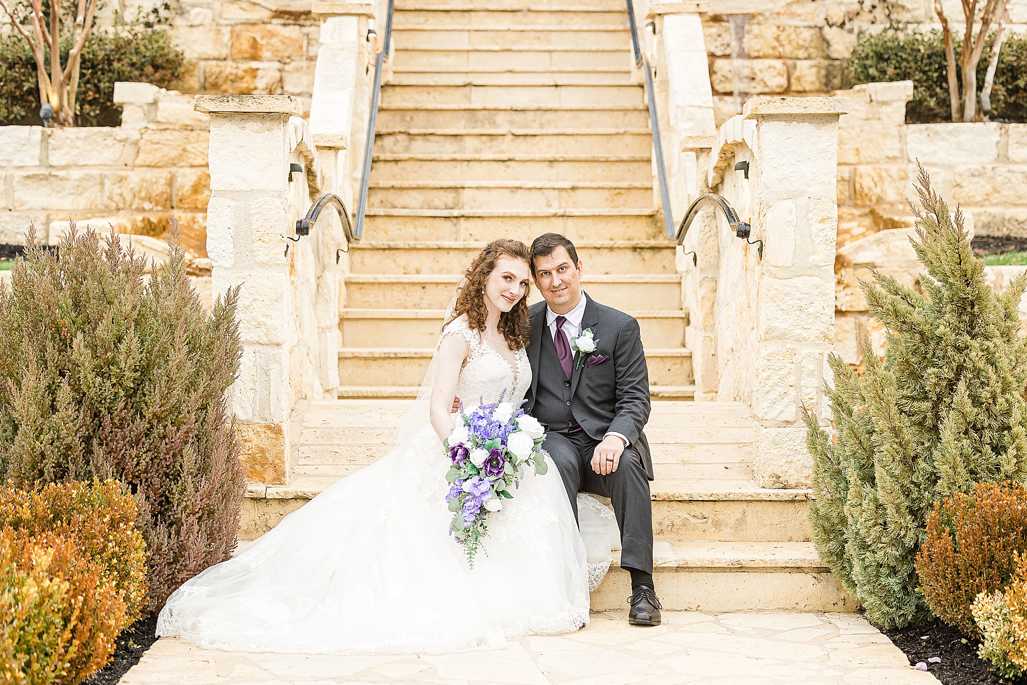 newlyweds sit on steps at Stone Hall at the Springs