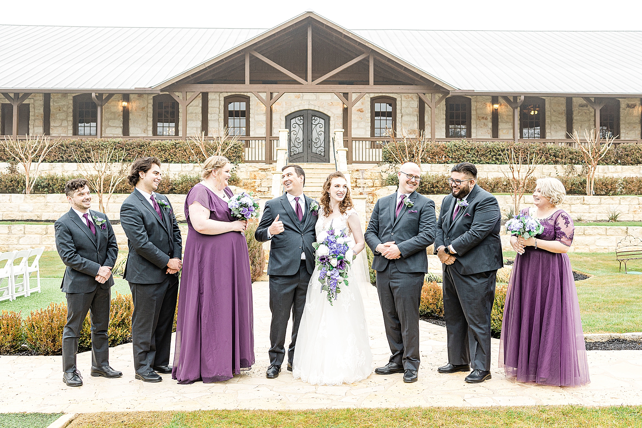 bride and groom laugh with wedding party outside Stone Hall at the Springs