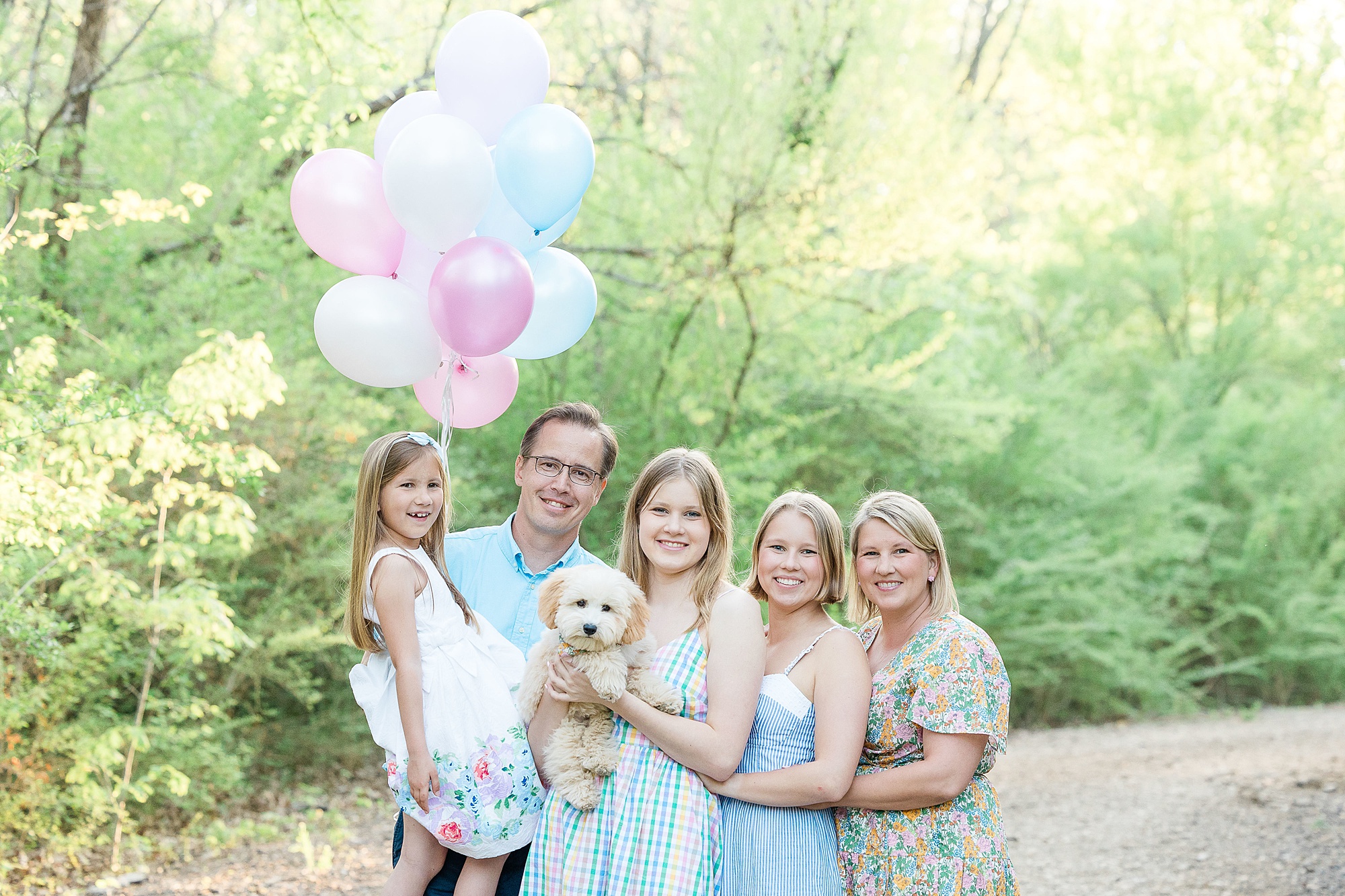 family of five poses with dog holding balloons
