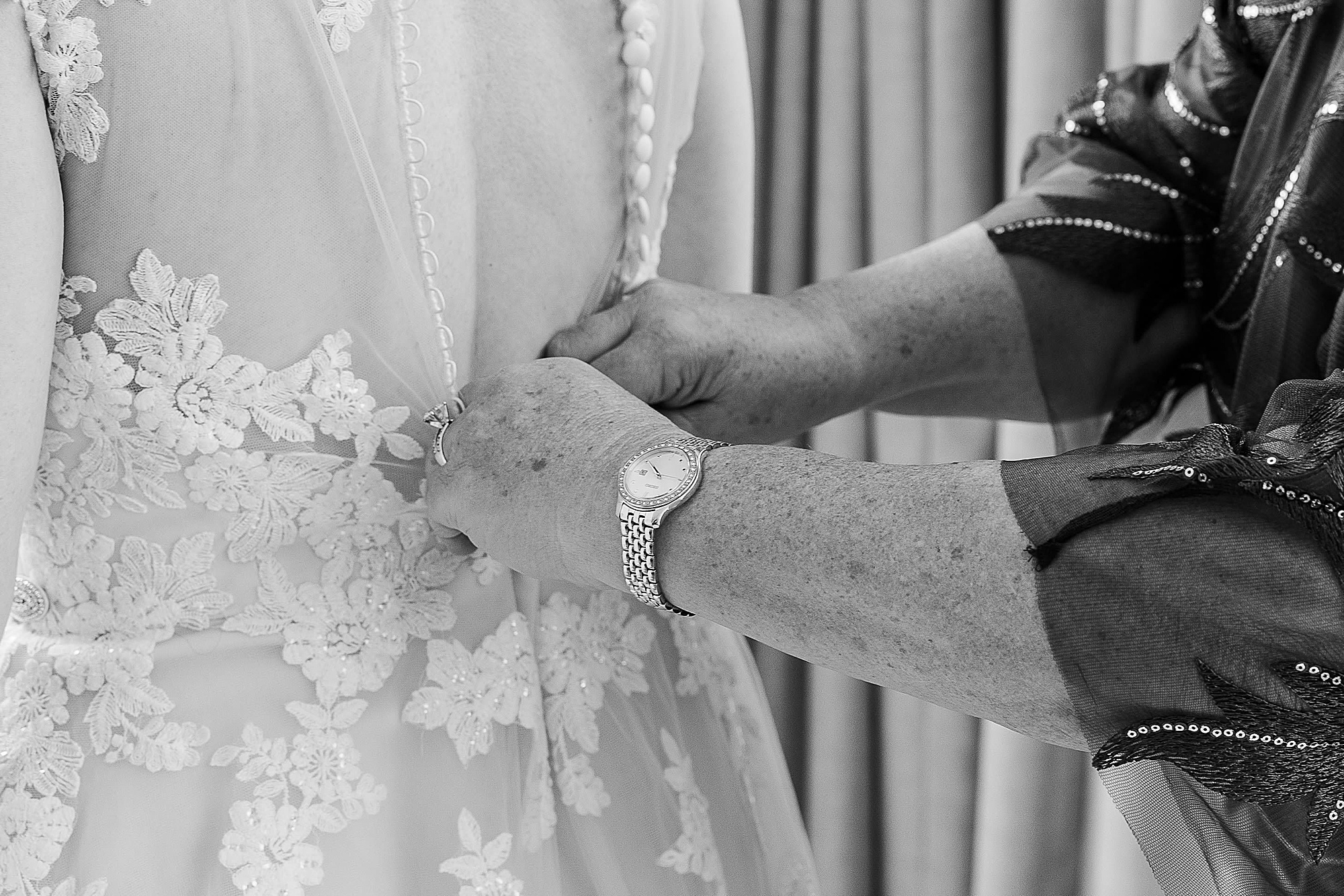 mom helps bride with wedding gown