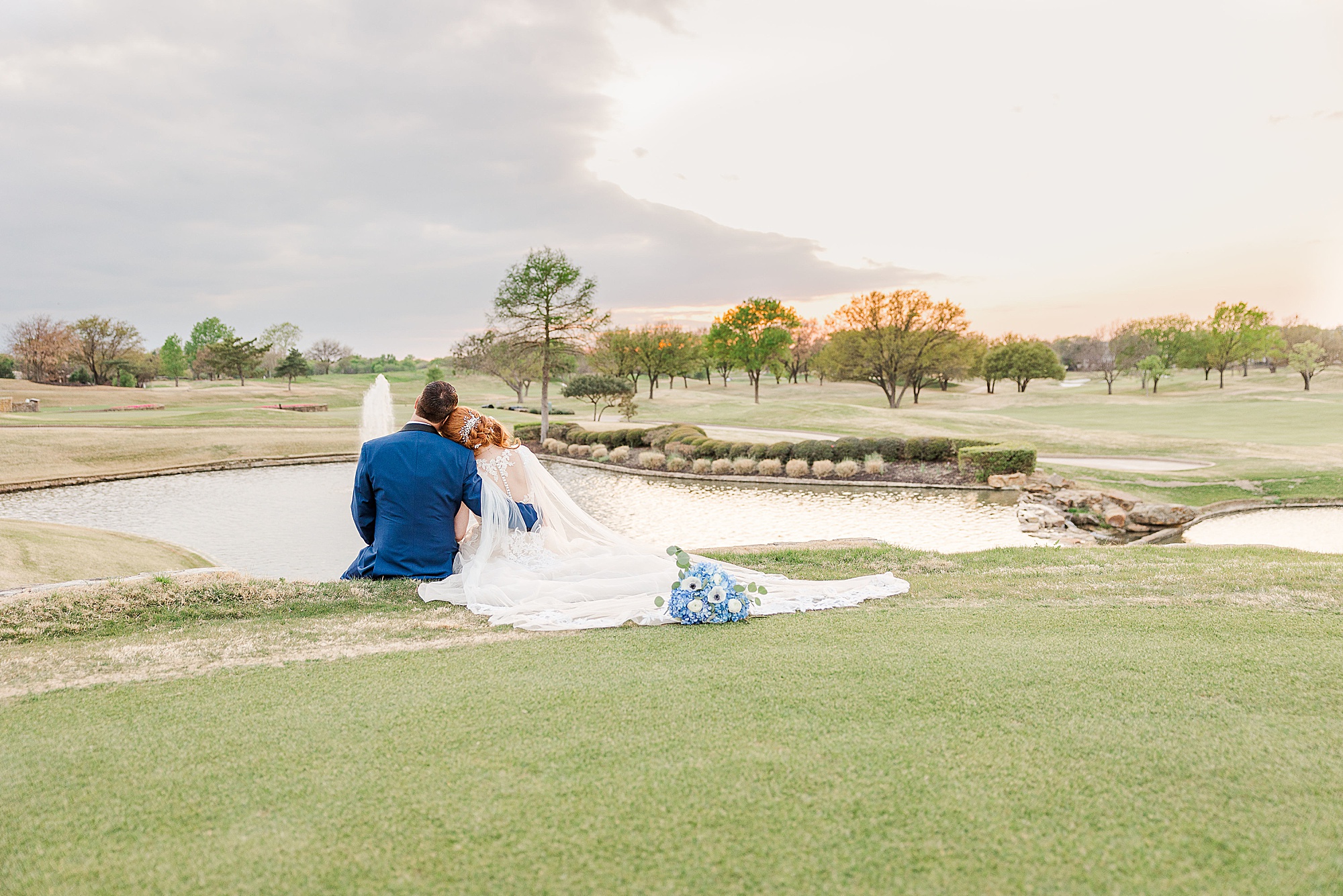 bride and groom sit by lake at sunset at Stonebriar Country Club